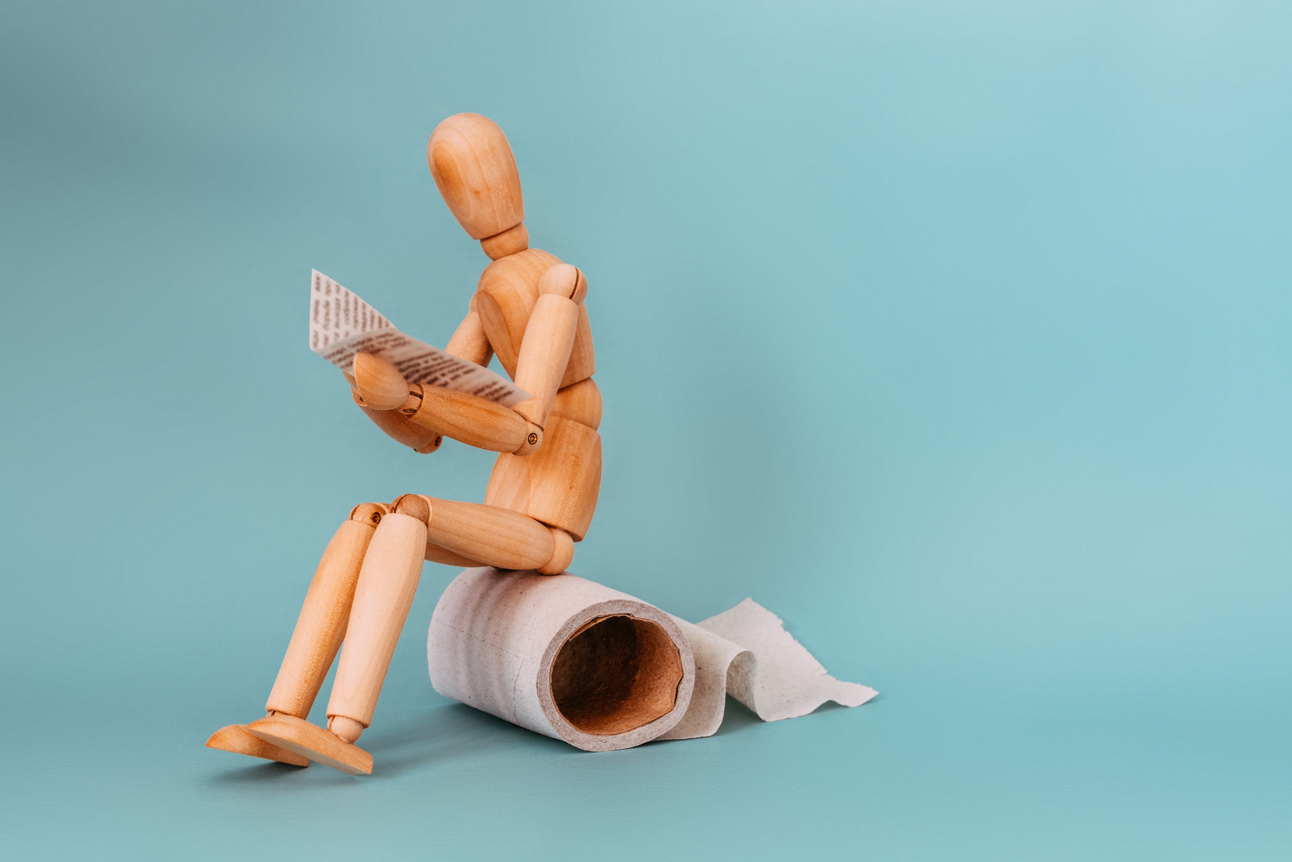 Wooden,figure,sit,on,a,roll,of,toilet,paper,and